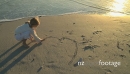 LS OF A GIRL DRAWING A HEART IN THE SAND 17840